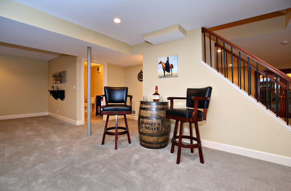 Louisville Basement Stairs with Barrell and Two Bar Chairs And A Spcaicous Room